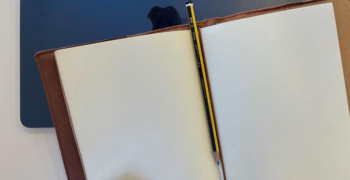 foto de um caderno aberto com um lápis no meio das páginas